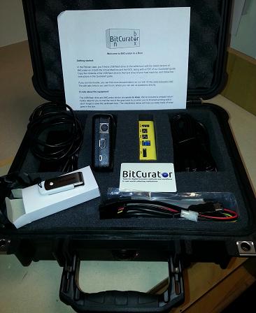 Photo of the BitCurator in a Box. Includes two write-blockers, cables and cords, and BitCurator program on a USB drive